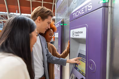 A group of people buying tickets at a ticket machine