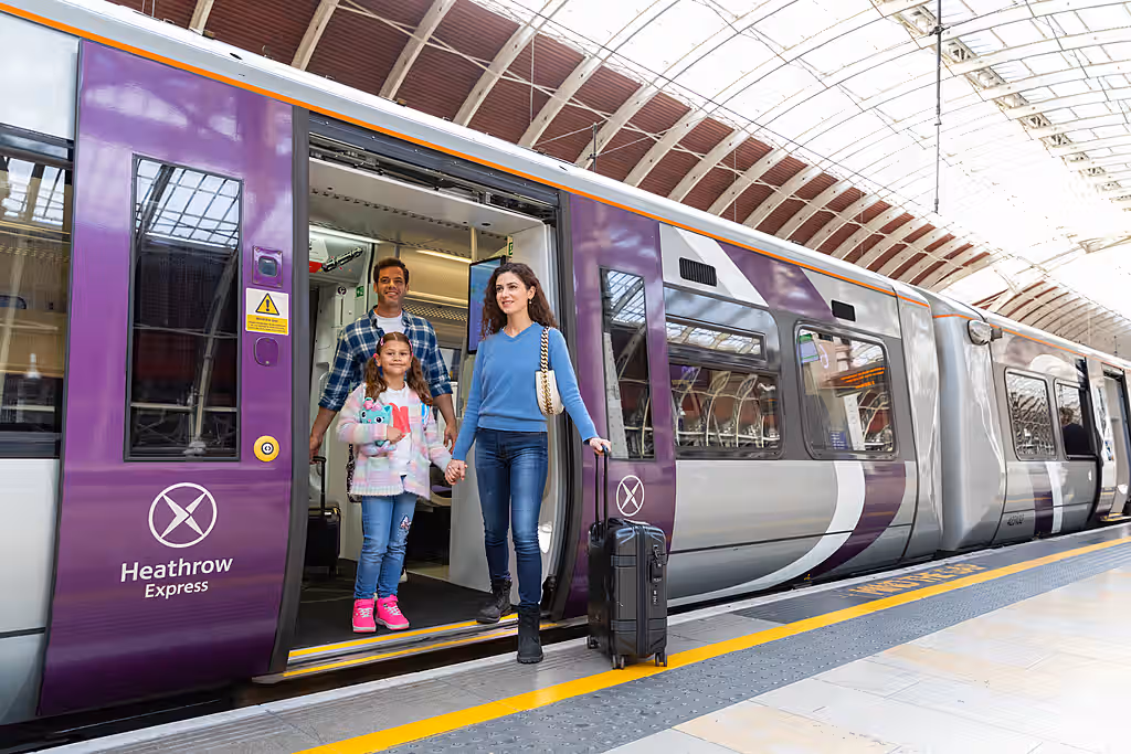 A family consisting of a mother, father and child exiting the Heathrow Express with their luggage